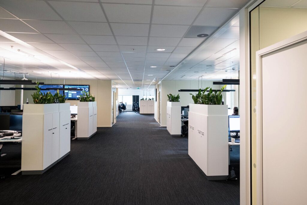 Åpent kontorlandskap med arbeidsplasser etter ombygging.